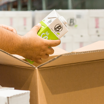 Online Shop Symbolbild für den Shop: Jemand verpackt einen Getränkekarton von Berief