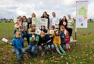 Sieger der Aktion grüner Kindergarten 2023 Kinder auf einer Wiese, die ein Plakat von Berief hochhalten.