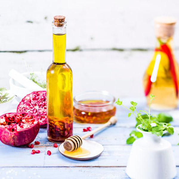 Ölguide Zwei Flaschen mit Öl auf weißem Tischtuch mit Früchten und Deko