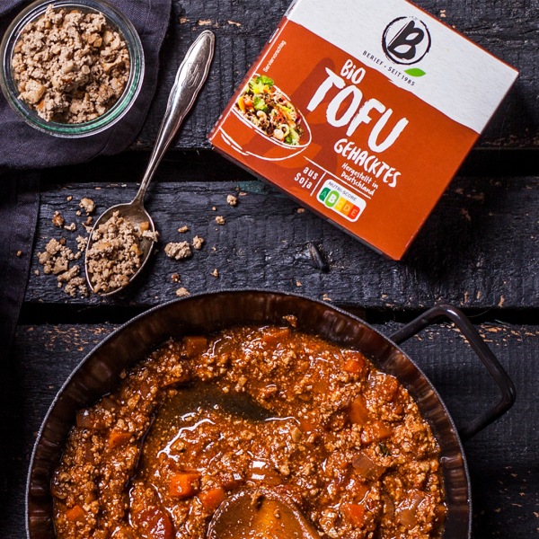 Pfannengeheimnisse Gußeiserne schwarze Pfanne mit Bio-Tofu-Gehacktes, daneben die Packung des Gehackten