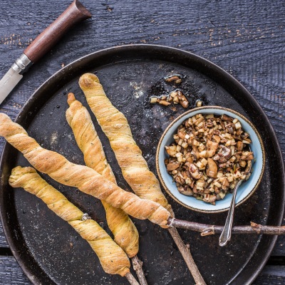 Stockbrot mit Kräutern Vier Stockbrote am Stiel mit einem Kräuterdip auf einem schwarzen Teller