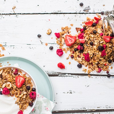 Selbstgemachtes Grenola mit getrockneten Beeren Grenola in einer weißen Schüssel mit Obst auf einem Tisch mit Früchten
