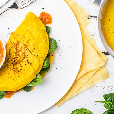 Veganes Omlette mit Tomatenchutney Zusammengeklapptes Omlett mit Füllung auf einem weißen Teller