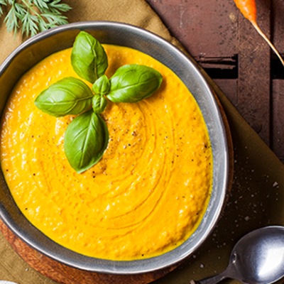 Möhren-Ingwer-Suppe mit Kurkuma Mören-Ingwer-Suppe in einer Schüssel ganiert mit Basilikum