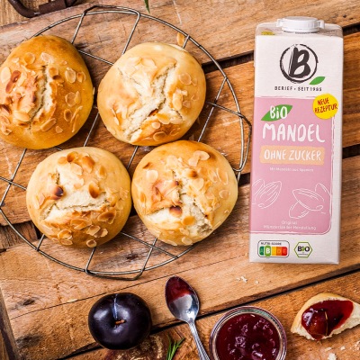 Brioches mit Mandeldrink Vier Brioches auf einem Glasteller mit Dekoration