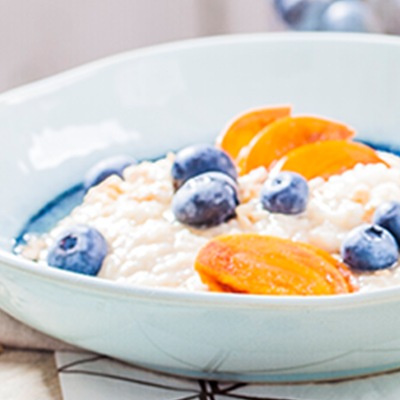 Veganer Milchreis Milchreis mit Früchten in einem weißen Teller