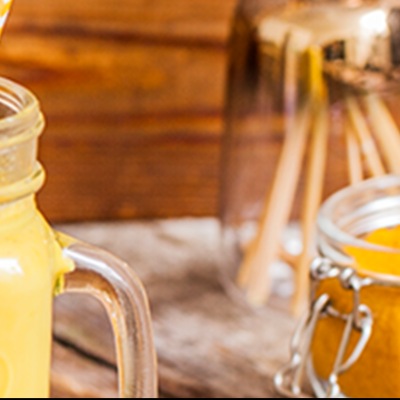 Veganer Kurkuma-Latte alias goldene Milch Kräftig gelbgefärbte Getränk in rustikalen Gläsern mit Dekoration