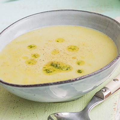 Erbsen-Spargel-Suppe Cremfarbige Suppe in einer hellen Tonschale garniert mit Kräutern