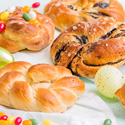 Vegane Hefekränze Hefekränze mit bunten Zuckerperlen auf einem weißen Tischtuch