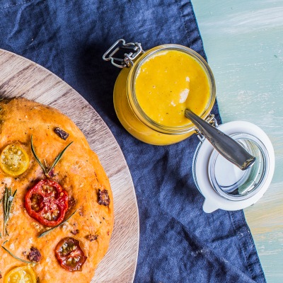 Mango-Curry-Dip Mango-Curry-Dip neben einem Fladenbrot in einem Glas auf blauem Tischtuch