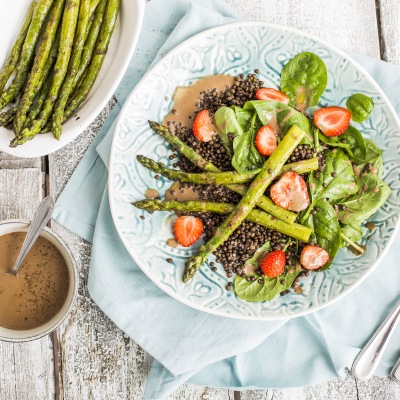 Spargelsalat- mit-Erdbeeren und Balsamico-Vinaigrette Spargel und Erdbeeren auf Blattsalat und Linsen mit Dip Dip auf einem Tisch.