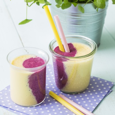 Mango-Beeren-Lassi Zwei bunte Getränke mit Strohhalm mit Dekoration
