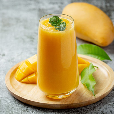 Mango-Lassi Mango-Lassi auf einem Holzteller mit Dekoration