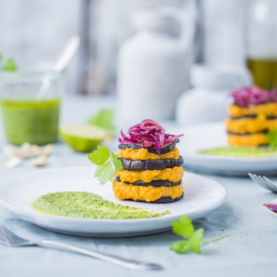 Süsskartoffel-Auberginen-Tuermchen Abwechselnd geschichtete Süßkartoffel-Auberginen auf einem Teller mit Dekoration.