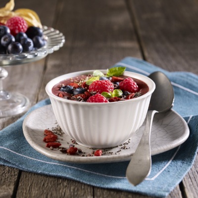 Power-Bowl mit Beeren und Superfood-Topping Eine kleine Schale mit Bowl und Früchte-Topping nebst Dekoration.